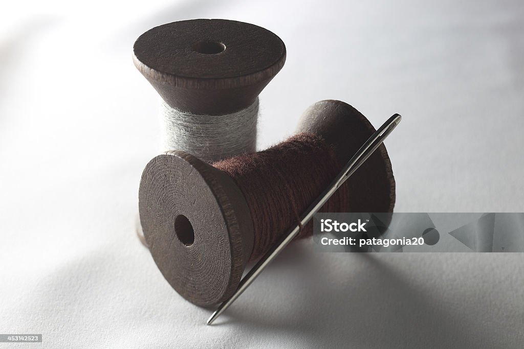 Antique Thread and Needle Two wooden antique thread spools with a large needle. Antique Stock Photo