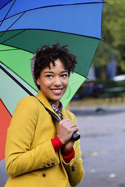Good-looking black girl with yellow jacket and umbrella stock photo
