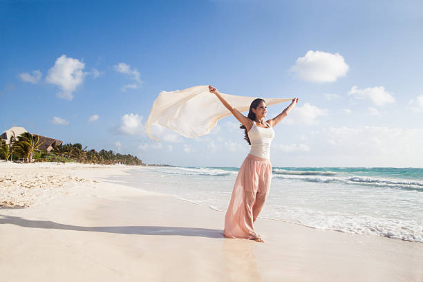 bellissima donna felicemente camminare sulla spiaggia - wind scarf women people foto e immagini stock