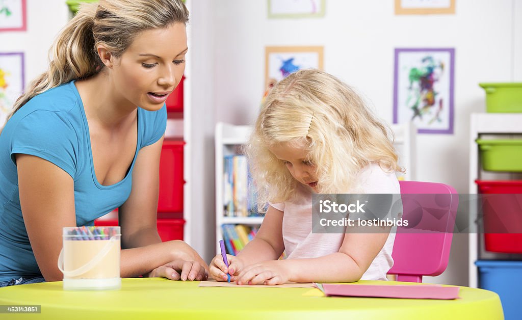Little Caucasian Girl And Her Carer During Artwork A portrait of a little caucasian girl drawing under her carer's supervision during art and craft. 20-29 Years Stock Photo