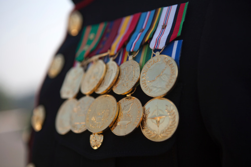 Expert Rifleman Medal focus in front of unfocused flag background.