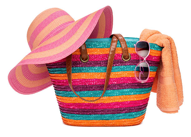 Colorful striped beach bag with straw hat towel and sunglasses Colorful striped beach bag with a straw hat towel and sunglasses, isolated on white beach bag stock pictures, royalty-free photos & images