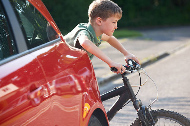 enfant équitation de vélo de stationnement de voiture - child bicycle cycling danger photos et images de collection