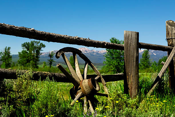 An old wagon wheel leaning on wooden rail fence shows extreme weathering. It is broken and fragile with history possibly stemming from over 100 years ago. This image accurately portrays wild west atmosphere. SEE MORE LIKE THIS... Similar images in the Lightboxes featured below.