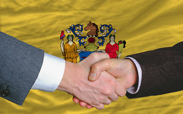 in front of american state flag new jersey two businessmen two businessmen shaking hands after good business investment agreement in front US state flag of new jersey jerseyan stock pictures, royalty-free photos & images