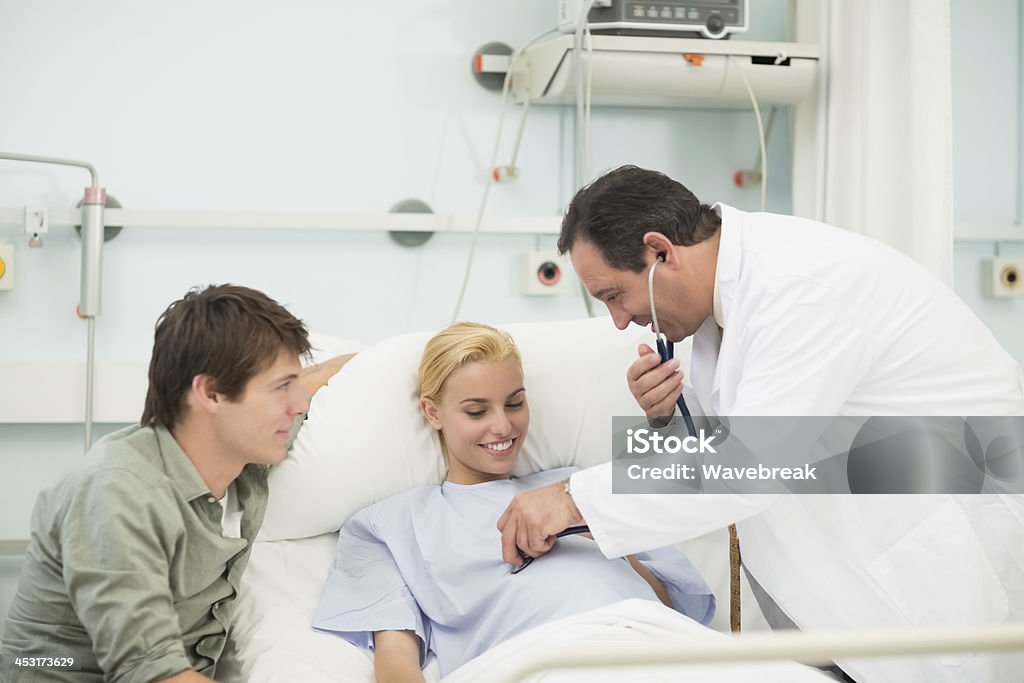 Obstétrico sonriendo mientras usando un estetoscopio - Foto de stock de Embarazada libre de derechos