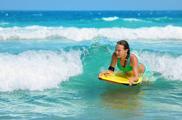 Young attractive woman bodyboards on surfboard with nice smile stock photo