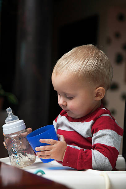 istock baby boy playing with bottle and mug indoor 453179177