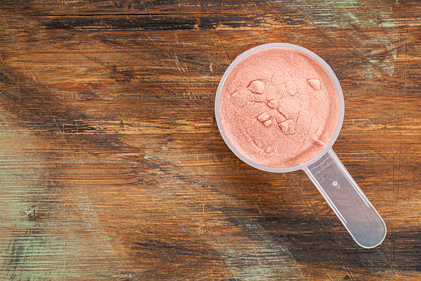 pomegranate fruit powder measuring scoop of pomegranate fruit powder - top view against painted wood background superfruit stock pictures, royalty-free photos & images