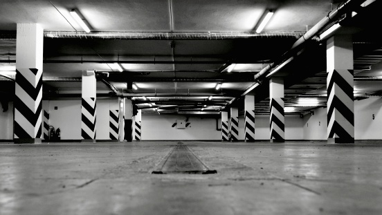 Black and white photo of empty underground parking garage. Shot in wide angle.