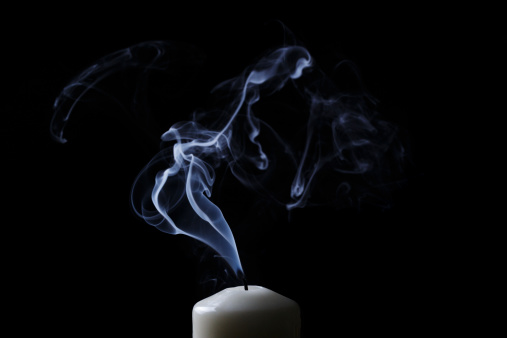 extinguished candle with blue smoke, black background