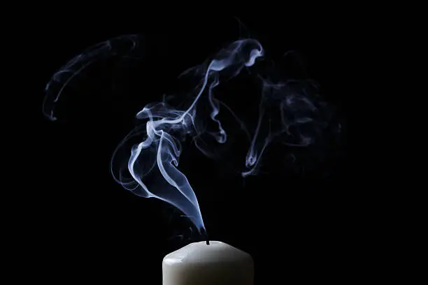 Photo of extinguished candle with blue smoke