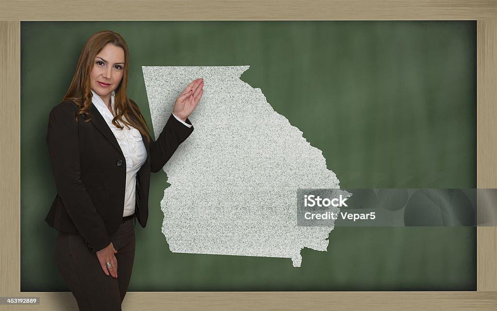 Teacher showing map of georgia on blackboard Successful, beautiful and confident young woman showing map of georgia on blackboard for presentation, marketing research and tourist advertising Adult Stock Photo