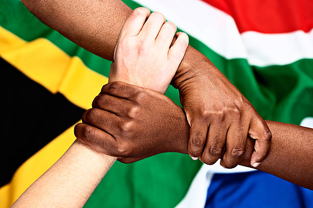 istock Rainbow nation unity: three clasped hands against South African flag 453194617