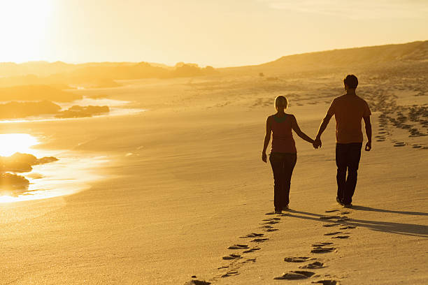 istock Couple Holding Hands While Walking On Beach At Sunset 453196413