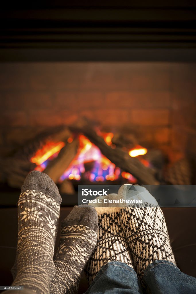 Feet warming by fireplace Feet in wool socks warming by cozy fire Winter Stock Photo