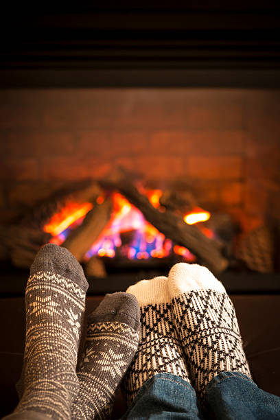 Feet warming by fireplace Feet in wool socks warming by cozy fire heat home interior comfortable human foot stock pictures, royalty-free photos & images