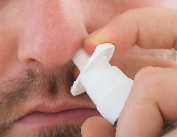 используя назальный спрей - nasal spray allergy bottle body care стоковые фото и изображения