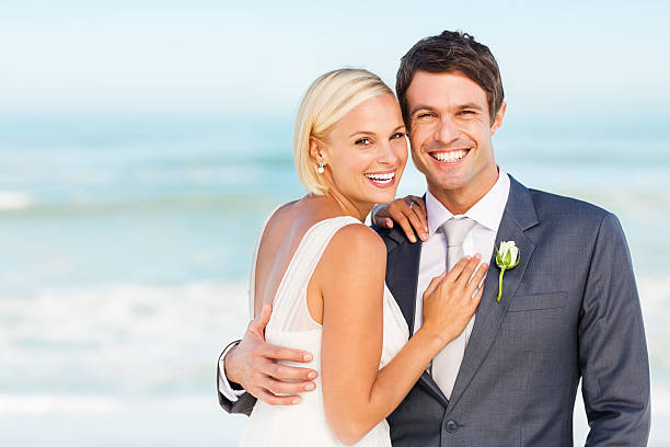 istock Groom Standing With Arm Around Bride On Beach 453205809