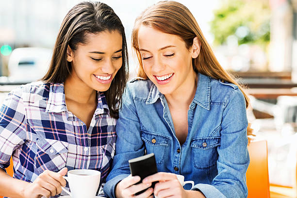 istock Female Friends Reading Text Message On Phone At Cafe 453205885