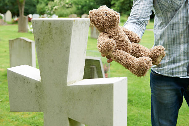 ojciec umieszczenie miś na child's grave w cemetery - cemetery child mourner death zdjęcia i obrazy z banku zdjęć