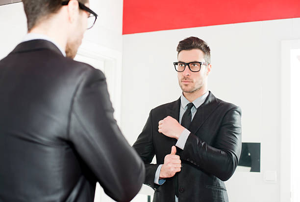 Young handsome man fix his suit Young handsome man fix his suit in the mirror necktie fashion adjusting suit stock pictures, royalty-free photos & images