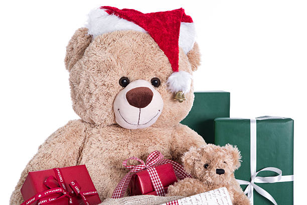 istock Teddy bear wearing Christmas hat with red gifts isolated. 453229189