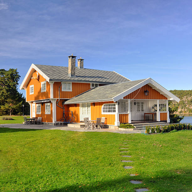 Orange-white norwegian country family house with green yard.