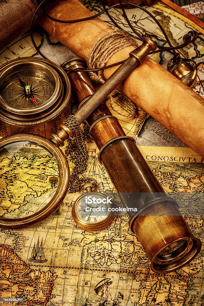 Vintage still life. Vintage magnifying glass, compass, telescope and a pocket watch lying on an old map. Abstract Stock Photo
