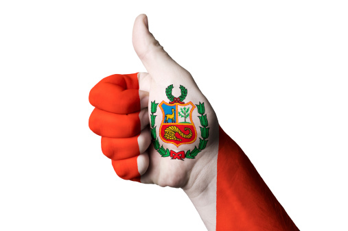 Hand with thumb up gesture in colored peru national flag as symbol of excellence, achievement, good, - for tourism and touristic advertising, positive political, cultural, social management of country