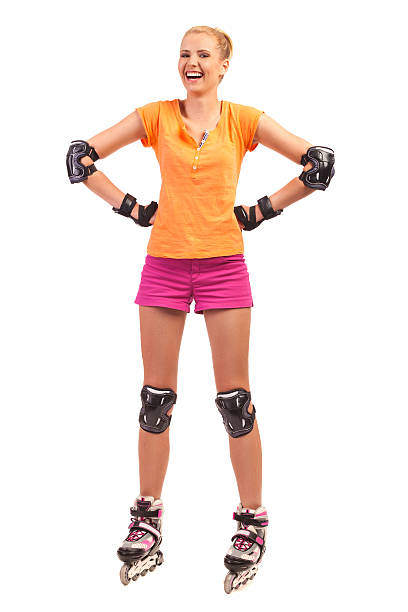 Laughing Woman on rollerblades. Young attractive woman on rollerblades standing with hands on hips. Full length studio shot isolated on white. elbow pad stock pictures, royalty-free photos & images