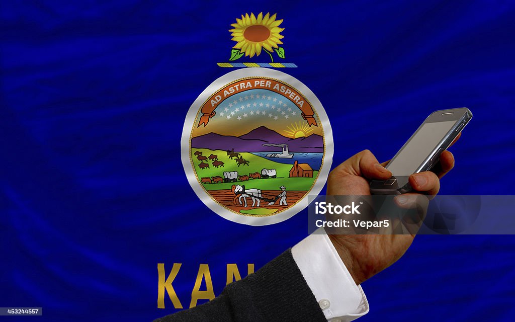 cell phone in front  flag of american state kansas man holding cell phone in front flag of us state of kansas symbolizing mobile communication and telecommunication Close-up Stock Photo