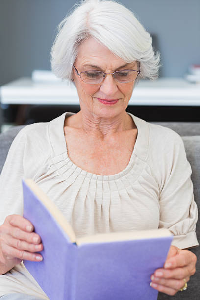 istock Smiling mature woman reading on sofa 453248933