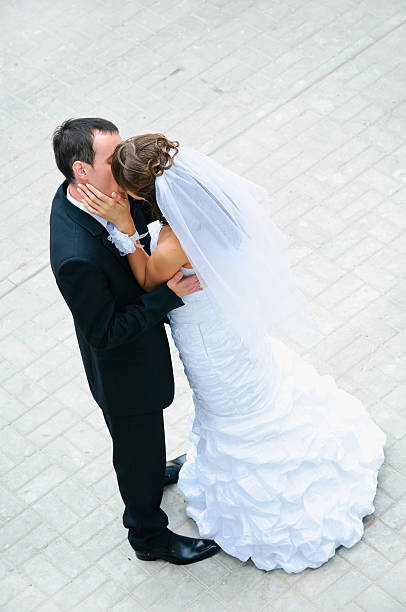 istock happy wedding couple standing, kissing and embracing 453250537