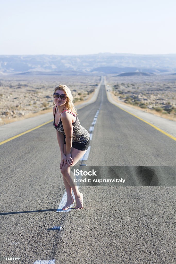 Beautiful young woman  on a road . Beautiful  woman posing on a road over picturesque landscape. Adult Stock Photo