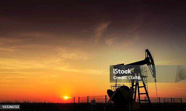 An Oil And Gas Well Operating During Sunset Stock Photo - Download Image Now - Fracking, Crude Oil, Shale