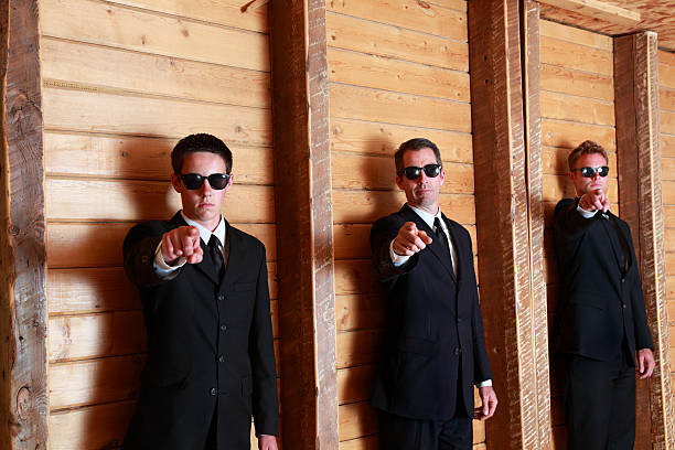 istock three men in black point at camera with danger menace 453274867