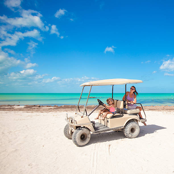 istock two daughters and their mother driving golf cart at beach 453276765