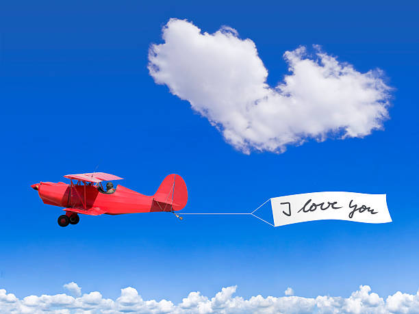 Red biplane with a banner and a cloud like a heart