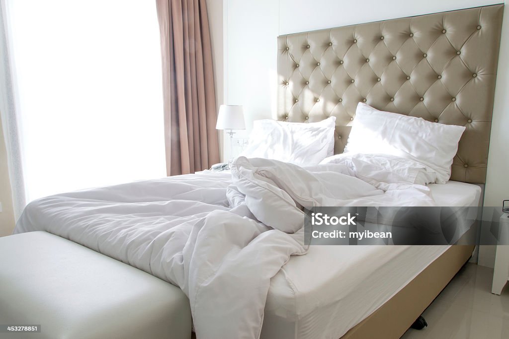 Unmade bed on a modern bedroom in light colors messy bedding sheets and pillow Bed - Furniture Stock Photo