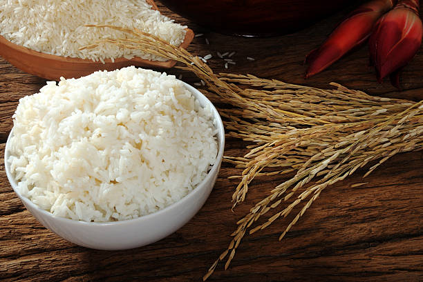 Cozinhado, não cozidas e arroz paddy na mesa de madeira - fotografia de stock