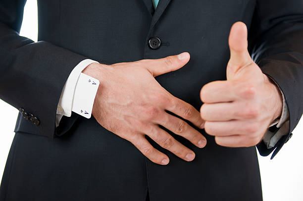 thumbs up doubtful Close-up of hands before the belly of a young man in a black suit, the thumb of the left hand pointing upwards, as well as a cross as game map in the right hand sleeve speaking with forked tongue stock pictures, royalty-free photos & images