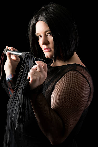 istock Side view of black haired dominatrix with flogger. 453304429