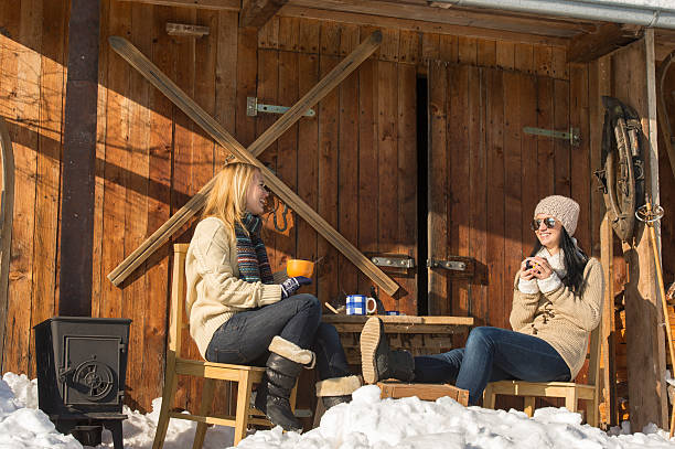 Two girlfriends enjoy tea winter snow cottage stock photo