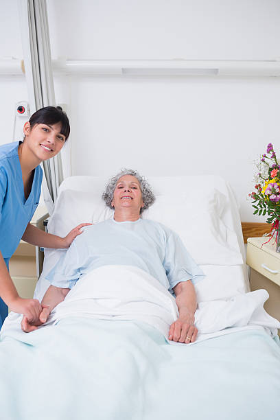 istock Smiling woman lying on bed while talking to a nurse 453312433
