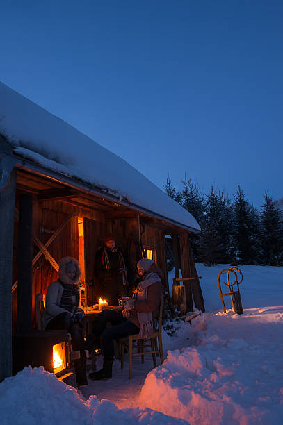 Pôr-do-sol do inverno amigos, desfrutando de uma cabana à noite - foto de acervo