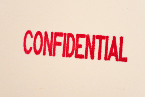A red confidential stamp on a manilla folder