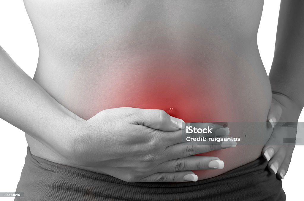 Woman holding her stomach which is glowing red Woman suffering from stomach pain, isolated in white, black and white with a red circle around the painful area Chronic Illness Stock Photo
