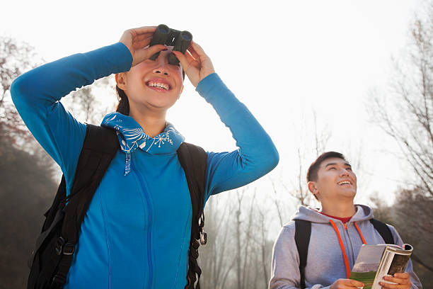 istock Young woman looking through binoculars, man standing in the background 453379327
