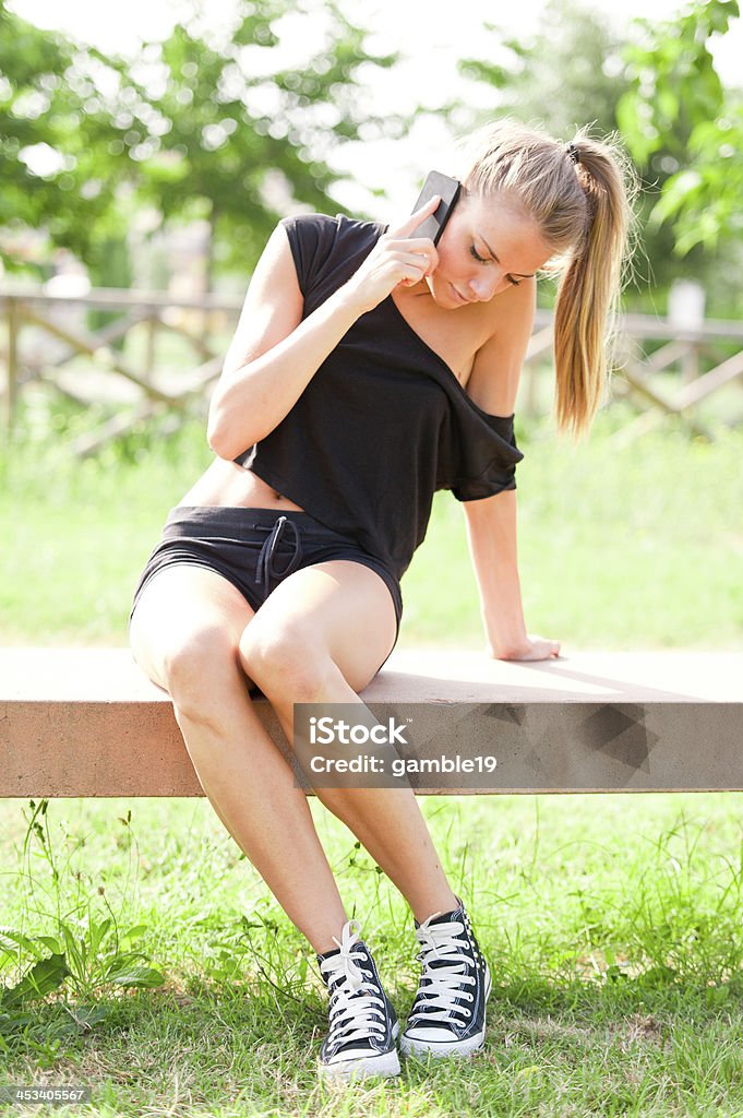 Young cute woman talking on the phone in city park Adult Stock Photo